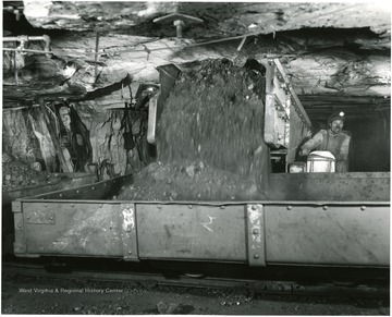 A miner watches as coal is loaded into mine cars from a shuttle car.