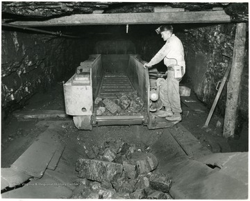 Miner works at unloading a shuttle car into an elevator.