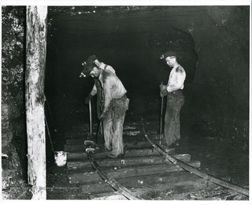 Three miners work on rail tracks in mine at Mill Creek.