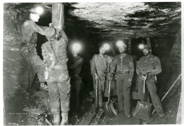 Miners place a piece of timber to support the roof of the mine.