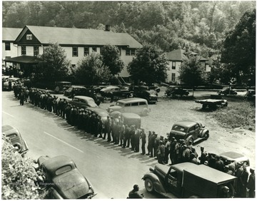 Miners stand in a line along a street.
