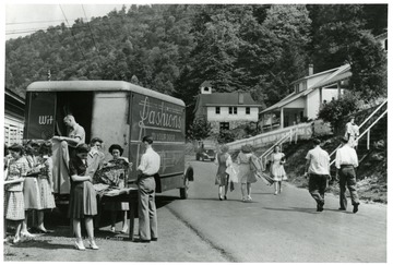 Women buy clothes from a man in a truck.