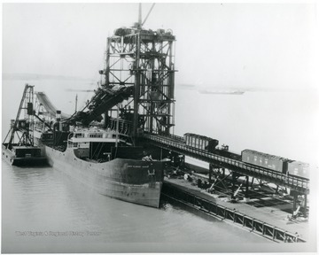 'Cars on Viaduct, dumper machine in operation placing coal in hatch of ship.'
