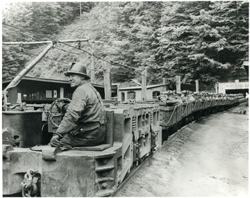 A man drives a locomotive hauling miners out of the Algoma mine.