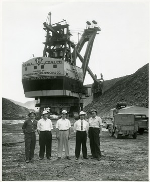 Group portrait of visitors in hard hats in front of the giant shovel the Mountaineer.