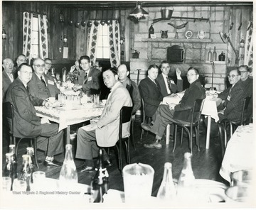 Group of men seated at tables.