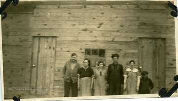 Family standing in front of a wooden barrack.