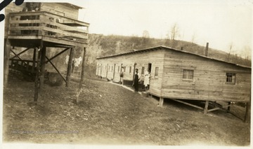 People standing outside and on porch of wooden barracks at Lumberport.