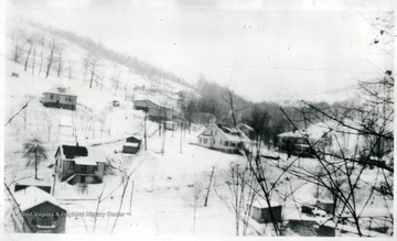 View of some snow covered houses with barracks in the distance.