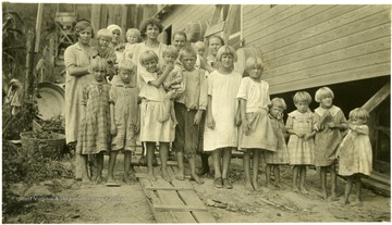 Group of women and children standing outside barracks.
