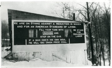 Sign reads, 'We ar on strike against a reductions in wages. And for an American standard of living. Fill your tank with unionism and step on the gas. We stand for organized labor. If a man owns his own soul, he will "dig" union price coal.' 
