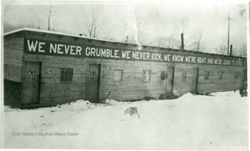 Union sign on front of barracks 'We never grumble, we never kick, we know we're right, and we're going to stick...' Snow covers the ground.