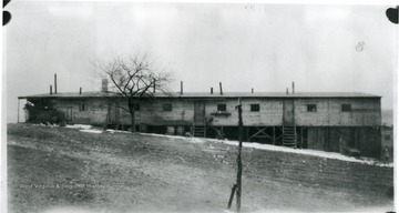 Barracks with tree in front at Rivesville, W. Va. with some snow and a girl standing on the right.