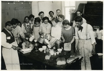 Men and women in kitchen preparing a meal.