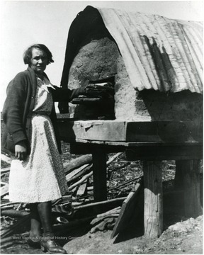 Picture of Mrs. Marin preparing a meal in her outdoor oven. 