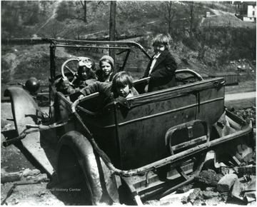 Picture presents unidentified girls playing in a wrecked car.