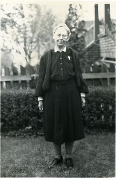 Julia A. Lakey, Director of Scott's Run 1924-1925 standing in front of hedges and wooden fence.
