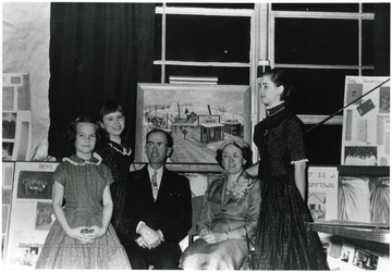 Group portrait of the Mary Behner Christopher family in front of a painting of the Shack.
