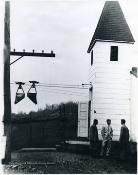 Three men stand outside Canyon Chapel church building. One of the Mountaineer Mining Mission Chapels, Monongalia County, W. Va. 'For information on the Mountaineer Mining Mission See A&amp;M 2491 (SC).'