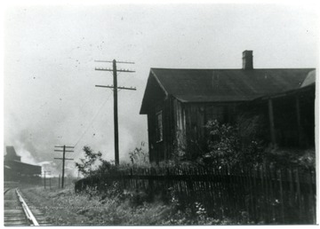 House with picket fence separating it from the railroad tracks.