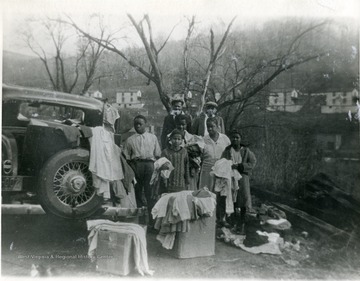 African-American family stand beside a car holding clothing. 'For more information on Mountaineer Mining Mission, see A&amp;M 2491 (S.C.)'