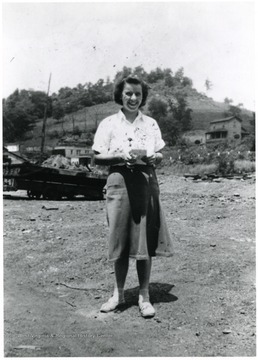 Woman smiling for picture. There is a house in the background.