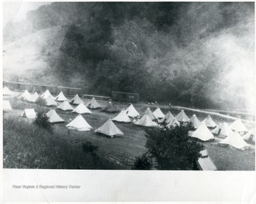 Tent camp with Chesapeake and Ohio train cars visible in the background.