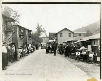 Miners and their belongings line the street below company houses.