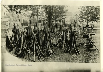 'Arms and ammunition surrendered to or captured by state troops immediately after first declaration of martial law on Paint Creek and Cabin Creek, September 2, 1912. See book, page 32, etc. Picture used on page 32 of book by H. B. Lee. Rifles, machine guns, pistols, and ammunition seized by the militia in the strike zone. Boxes on the left contain 225,000 rounds of machine gun ammunition.'
