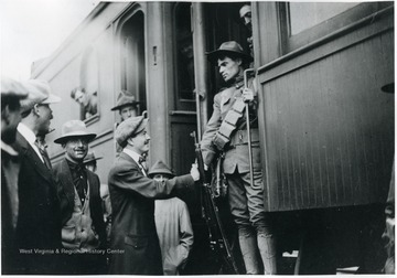 A trooper on a train shakes the hand of a man on the platform.