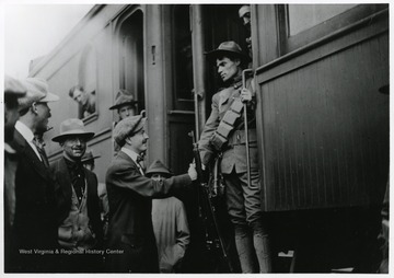 A trooper on a train shakes hands with a man on the platform.