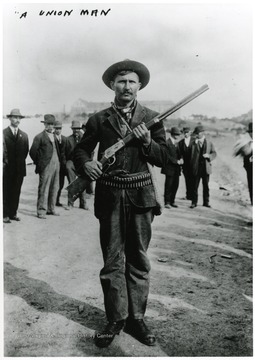 A union man standing with his rifle and ammunition.  Other men standing behind him.