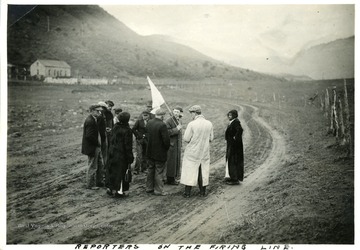Men and women standing on a firing lane holding a white flag.