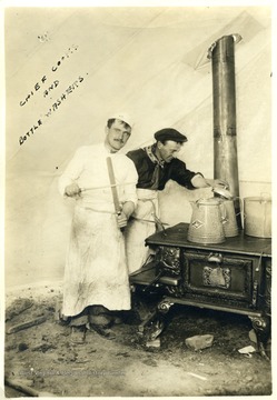 Two men working over a stove. 