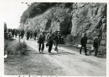 Miners walk along a road with their lunch pails at the Williams River Mine in Webster County.  Gauley Mountain Coal Company, Ansted, W. Va. 'Taken in mechanization' written on the front of the photograph.
