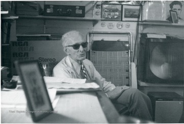 Unidentified man with sunglasses on seated at a table.