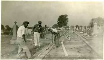 Three men construct wooden forms for a driveway in the Miner's Cemetery in Mt. Olive, Ill.