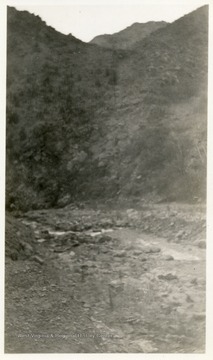 Creek with rocks visible beside a hillside.