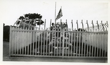 Men standing around a fenced in memorial/grave.