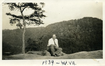 Ben Kunz sitting on a rock.  Mountains in the background.