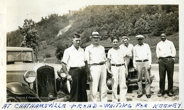 Six men with two cars on a road 'waiting for Keeney.'  Photograph from Joe Ozanic scrapbook.