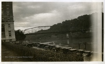 Cars parked in a parking lot beside a river. Photograph from Joe Ozanic scrapbook.