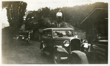 Young boy standing on the roof of a car. 