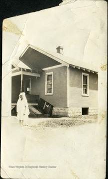 Small girl wearing a veil outside of a house. 