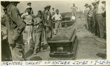 Workers stand around the uncovered casket of Mother Jones.