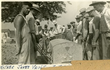 Men lift the vault from the grave site. 