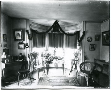 Ornate chairs, many portraits, and a garland strung over the windows decorate this room.