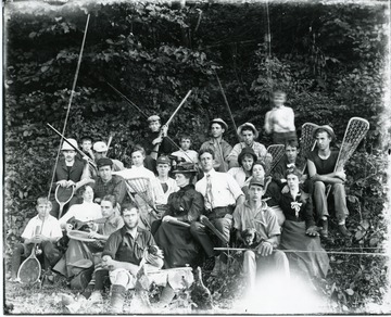 Male and female students from Allegheny Collegiate Institute, dressed in a variety of uniforms and outfits, hold equipment for several sports including lacrosse sticks, tennis rackets and fly-fishing poles.