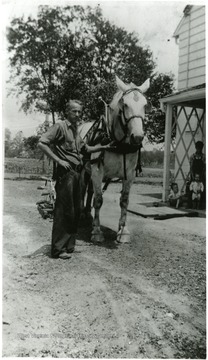 Frank E. Davis, Sr. stands next to a horse at Homestead Q.