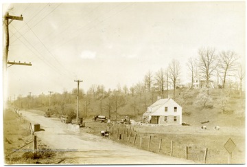 House on a hill overlooking a house beside the road.
